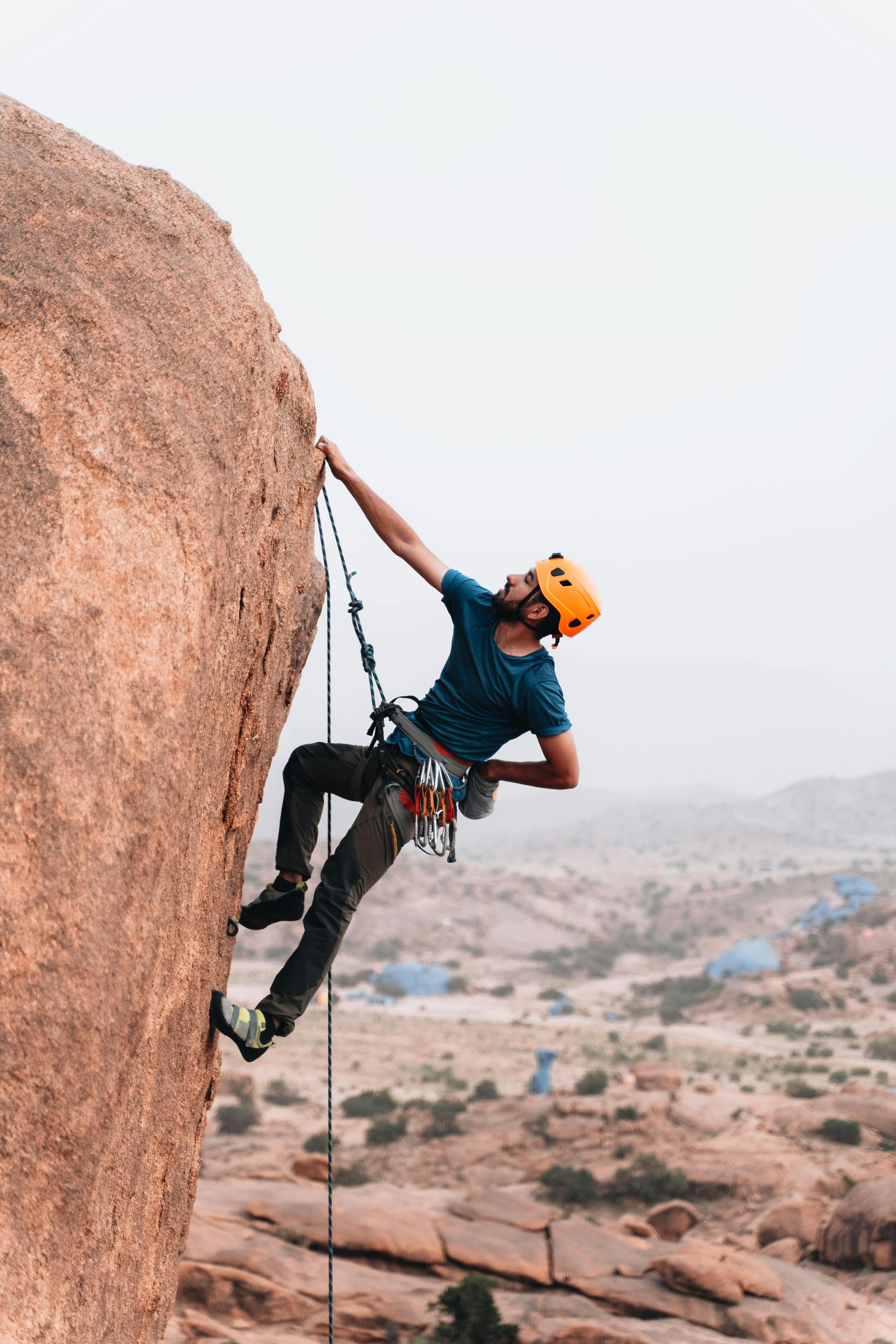 A man with rock climbing gear hanging from a rock face
